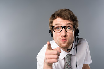 angry call center operator in headset and glasses pointing with finger at camera