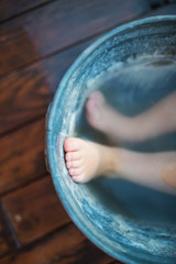 Midsection of children's feet in bath outdoors in garden in summer.