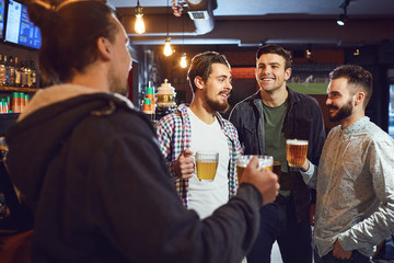 Friends talk, drink beer in a bar.