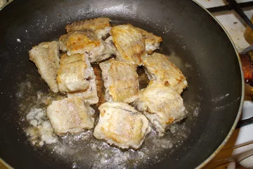 Deurstickers fried fish cooking in a pan © Andrey