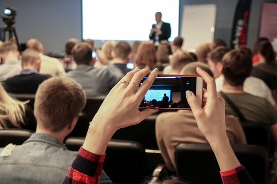 Woman takes a picture during the conference using smartphone
