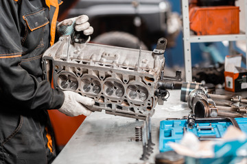 Mechanic disassembling the engine, overhaul.. Engine on a repair stand with piston and connecting...
