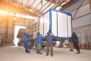 Men loaded transformer substation in a truck.