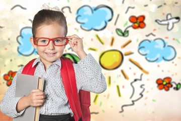 Cute little schoolgirl in glasses on blackboard background