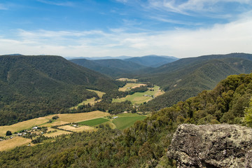 A valley seen from above. There are farms on the valley floor, and wooded mountains around. It is the upper King Valley, in Victoria, Australia, seen from Power's Lookout.