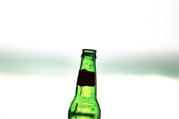 Empty 33cl bottle of beer close up, edited; sea view background. iconic image.