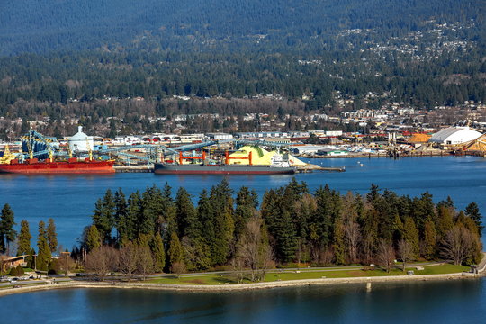 Terminal of North Vancouver port on a background of mountain scenery. The vessel is under load, the tug is towing another vessel.
