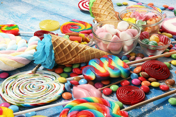 candies with jelly and sugar. colorful array of different childs sweets and treats on blue