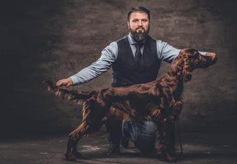 Middle-aged hunter dressed in elegant clothes sits on his knee and shows the full length of his...