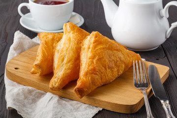 Puff pastry triangles filled with feta cheese and spinach on wooden table