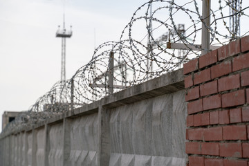 concrete fence with barbed wire against a gray sky