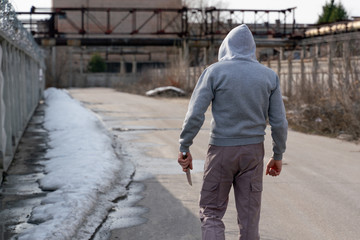 criminal with a knife in his hand goes to an abandoned building