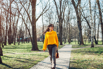 Young woman holding stylish handbag and wearing yellow sweater. Spring female clothes and accessories. Fashion