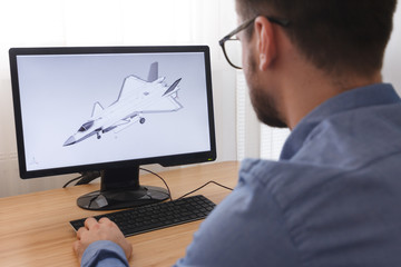 Engineer, Constructor, Designer in Glasses Working on a Personal Computer. He is Creating,...