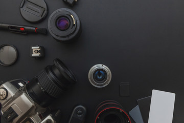 Photographer workplace with dslr camera system, camera cleaning kit, lens and camera accessory on dark black table background. Hobby travel photography concept. Flat lay top view copy space