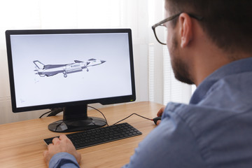 Engineer, Constructor, Designer in Glasses Working on a Personal Computer. He is Creating, Designing a New 3D Model of Aircraft, Airplane in CAD Program. Freelance Work
