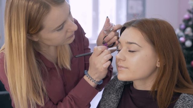 professional make-up artist the girl makes the shading of the shadows on the eyelid of the client 4K