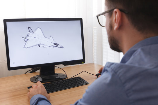 Engineer, Constructor, Designer in Glasses Working on a Personal Computer. He is Creating, Designing a New 3D Model of Aircraft, Airplane in CAD Program. Freelance Work