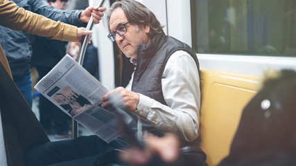 Man reading newspaper in the metro train