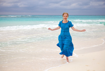 The woman in a long blue dress goes on the sea coast Cayo Largo island, Cuba