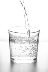 Water pouring into glass on white background