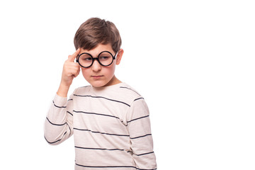 Studio shot of a serious boy  in round glasses, isolate with copy space. He thinks about something important putting his index finger to his temple