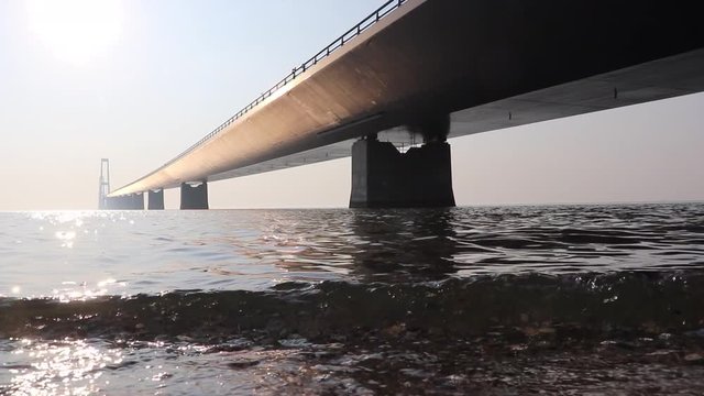 Storeb&aelig;ltsbroen in Denmark seen from sea level with reflecting sun