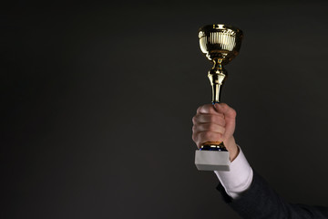 Businessman with a golden cup award trophy in hand. First place concept background. Best worker...