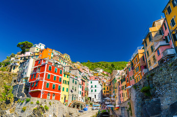 Fototapeta na wymiar Riomaggiore traditional typical Italian fishing village in National park Cinque Terre, colorful multicolored buildings houses on hill, clear blue sky copy space background, La Spezia, Liguria, Italy