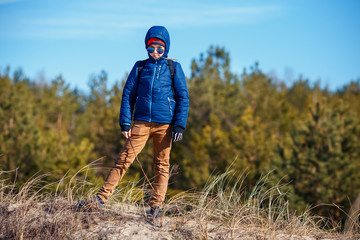 Naklejka premium Schoolboy wearing warm clothes and walking on spring beach to have fun, hike or just to feel fresh air