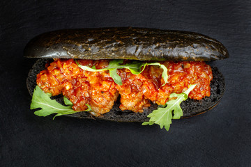 Black hot dog bun with minced meat.