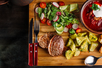 Lunch with fried meatballs, soup with meat and potatoes on a rustic.