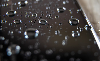 Back side of waterproof smartphone covered with drops of water