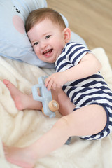 Baby boy is playing with wooden toys on the floor.