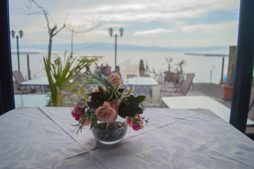 Fototapeta na wymiar Beautiful arranged table flowers sitting on a dining table with a lake few