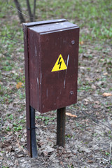 Rusty outdoor electricity meter board with a warning sign