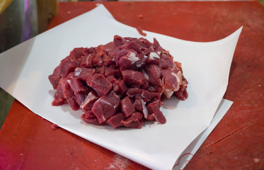 Cubed meats (Kusbasi et) on white paper in butcher shop. Closeup of red fatless meat cubes in supermarket. Fresh organic cow meat cuts on butcher board. Butchery, clean eating, diet concept background