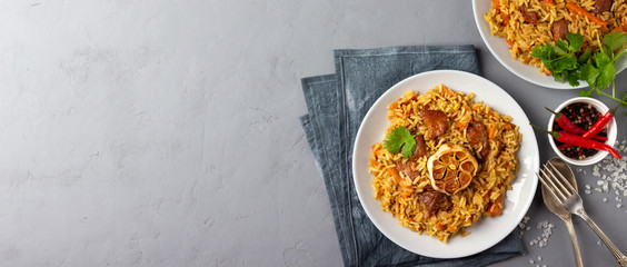 Traditional asian dish - pilaf from from rice, vegetables and meat in a plate on gray background. Top view with copy space.