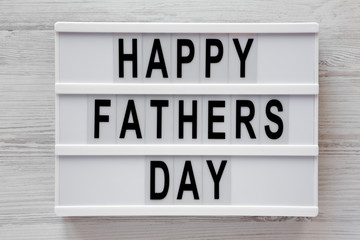 Lightbox with 'Happy Fathers Day' words over white wooden background, top view. Overhead, from above, flat lay. Close-up.