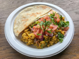 Indian curry vegetable meal with naan bread on paper plate