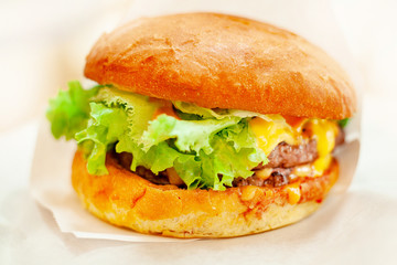 Cheeseburger Or Hamburger With Beef Cutlet, Tomatoes And Cheese Slices, Seasoned With Sauce And Green Salad On White Background.