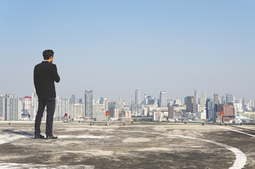 Fototapeta na wymiar Businessman looking city to the future on rooftop