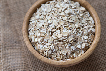 Uncooked oatmeal or oat flakes in a wooden bowl