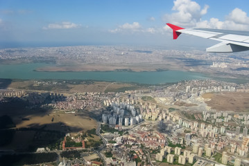 The view from the plane on the city. Turkey, summer, day. From the window you can see the wing of the plane.