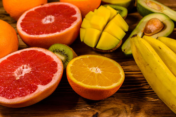 Still life with exotic fruits. Bananas, mango, oranges, avocado, grapefruit and kiwi fruits on wooden table