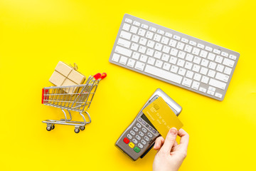 buying products with card machine, keyboard, credit card and mini trolley on yellow background top...