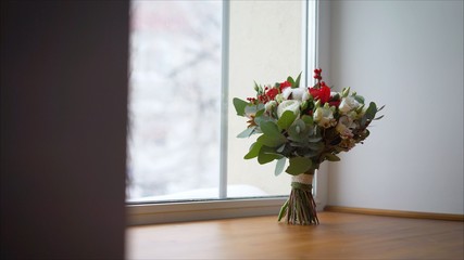 Beautiful wedding bouquet on the windowsill. bright red wedding bouquet of fresh flowers and eucalyptus stands on the windowsill
