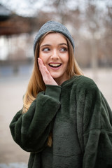 Portrait of happy smiling young blond woman with winter hat in a park in autumn	