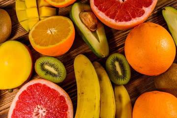 Still life with exotic fruits. Bananas, mango, oranges, avocado, grapefruit and kiwi fruits on wooden table. Top view