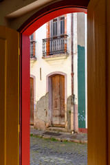 Old door in colonial architecture deteriorated by time seen through another door also old and with the same architecture in the city of Ouro Preto